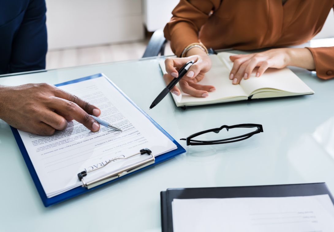 Two,businesspeople,hand,analyzing,document,over,glass,desk